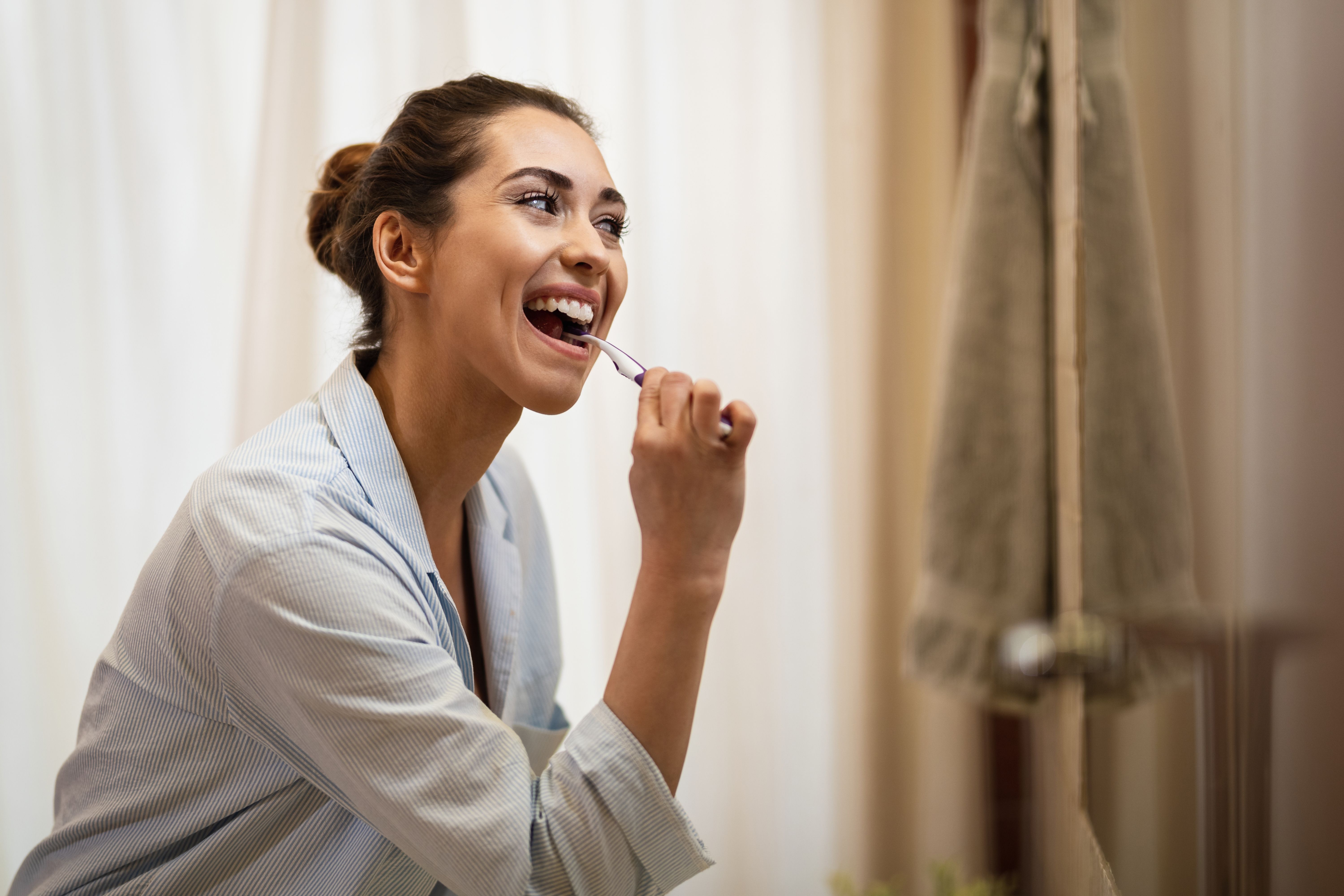 happy-woman-cleaning-her-teeth-with-toothbrush-morning