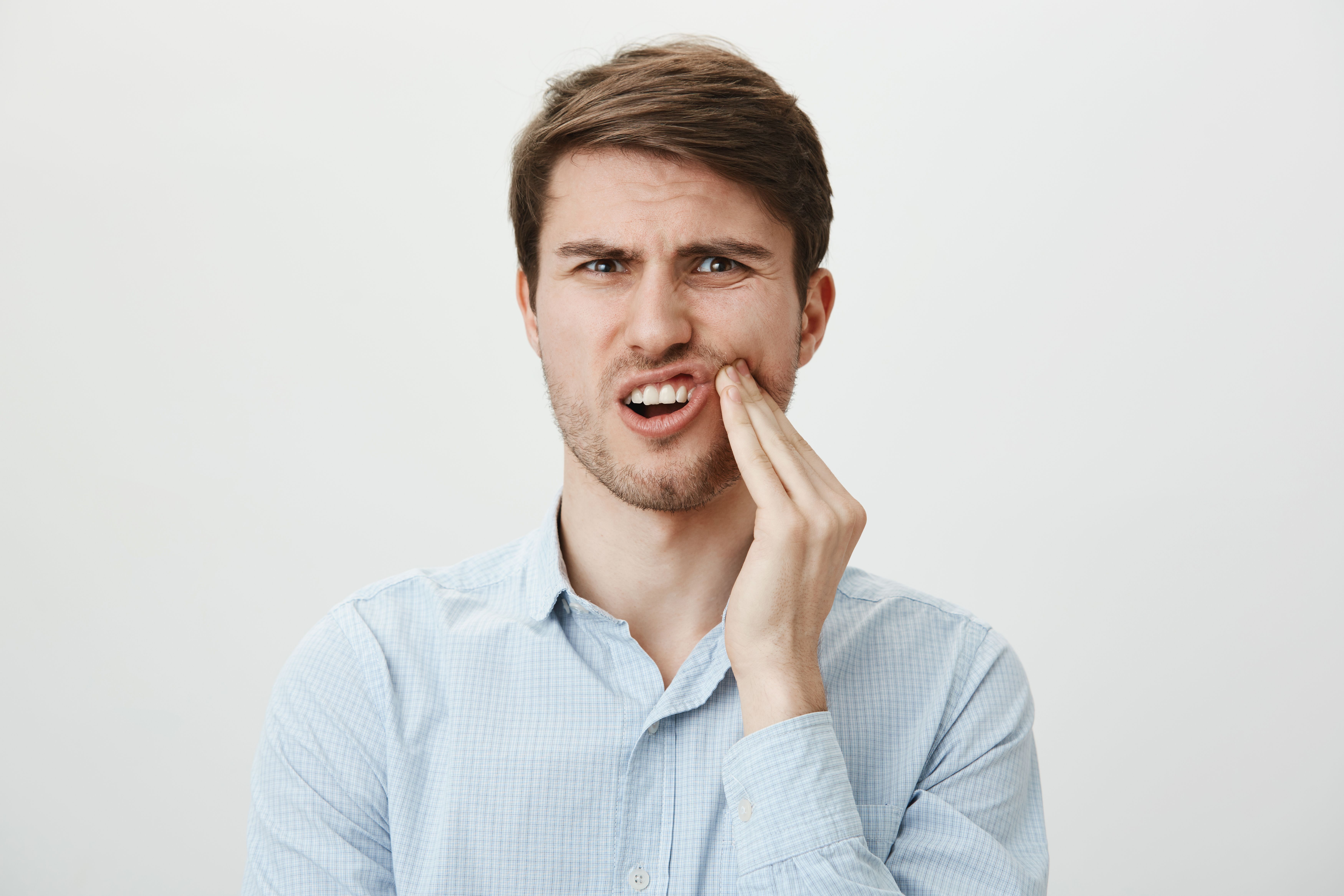 man-touching-cheek-grimacing-from-pain-from-toothache-need-dentist